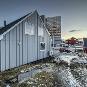 Snow-dusted houses and a modern apartment building at sunset in a coastal town
